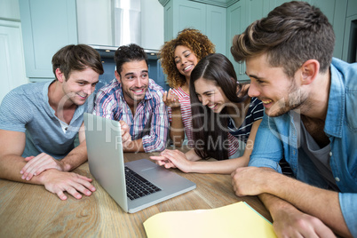Multi-ethnic friends laughing and looking in laptop