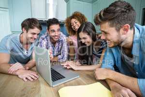 Multi-ethnic friends laughing and looking in laptop