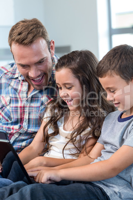 Father and siblings using digital tablet