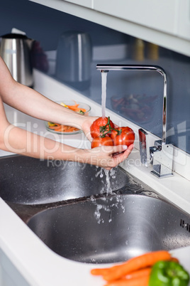 Woman washing tomatoes at kitchen sink