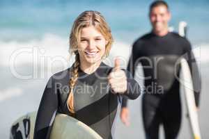 Happy woman with surfboard showing her thumb up