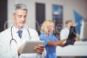 Male doctor using digital tablet with colleague checking X-ray