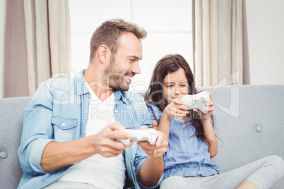 Father playing video game with daughter at home