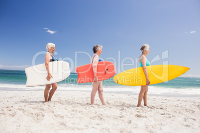 Senior woman friends holding surfboard