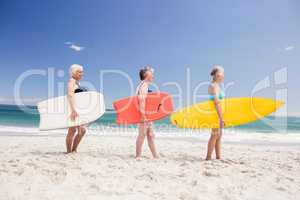 Senior woman friends holding surfboard