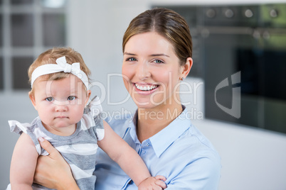 Happy mother carrying daughter at home