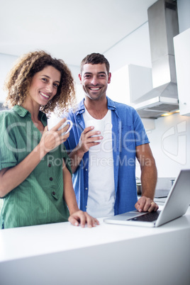 Portrait of couple using laptop while having a cup of coffee