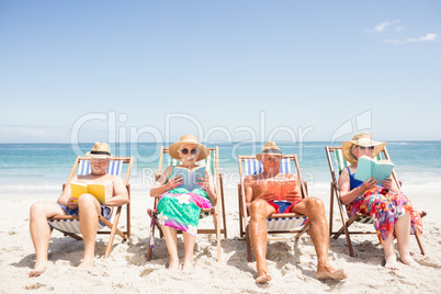 Senior friends reading books on beach chair