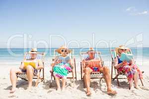 Senior friends reading books on beach chair