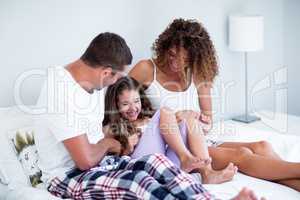 Happy couple and daughter enjoying together in bed