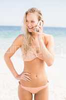 Pretty woman in bikini talking on phone at beach