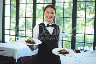 Smiling waitress holding plates