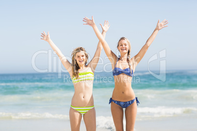 Excited women in bikini standing on the beach