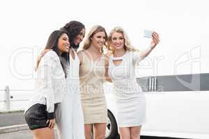 Well dressed women taking a selfie next to a limousine