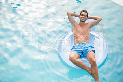 Shirtless man relaxing on inflatable ring