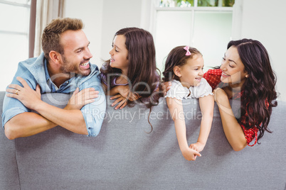 Happy parents with daughter on sofa at home