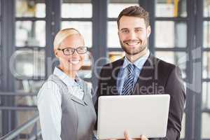 Happy business people with laptop standing in office