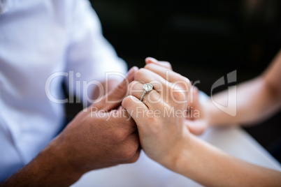 Close-up of couple holding hands with engagement ring