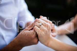 Close-up of couple holding hands with engagement ring