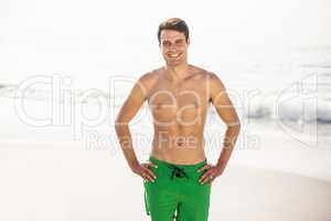 Portrait of man in swim shorts standing on beach