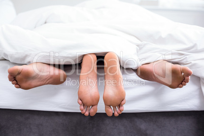 Low section of couple having sex on bed