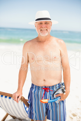 Senior man standing next to sunchair