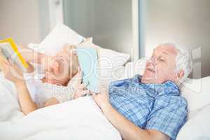 Senior couple reading while lying on bed