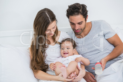 Young couple relaxing with baby on bed at