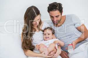 Young couple relaxing with baby on bed at