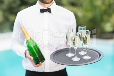 Waiter holding champagne flutes and bottle