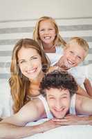 Portrait of smiling family on bed at home