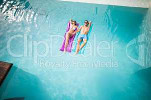 Couple relaxing on inflatable raft at swimming pool