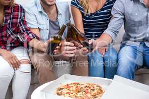 Friends enjoying beer and pizza at home