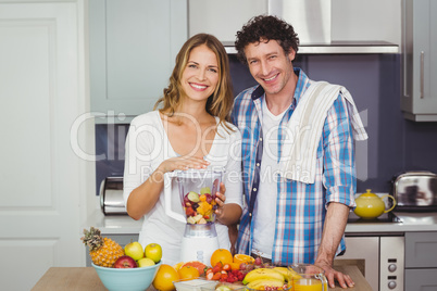 Portrait of cheerful couple preparing fruit juice
