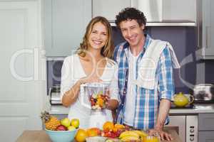 Portrait of cheerful couple preparing fruit juice