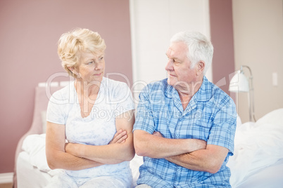 Serious couple sitting on bed at home