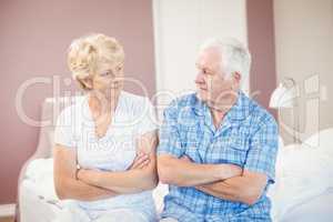 Serious couple sitting on bed at home