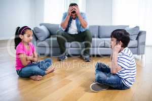 Annoyed father sitting on sofa while kids fighting