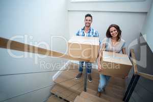 Portrait of happy couple holding cardboard boxes