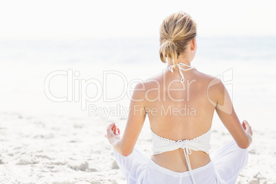 Rear view of woman performing yoga on the beach