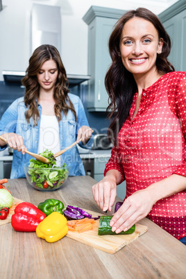 Happy female friends preparing salad