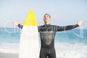 Happy man with surfboard standing on the beach
