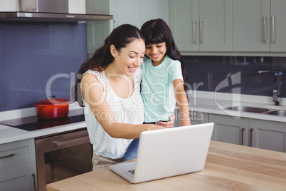 Smiling mother and daughter using laptop