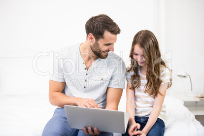 Father showing laptop to daughter on bed Father showing laptop to daughter on bed