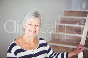Portrait of happy senior woman against staircase