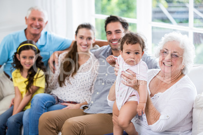 Portrait of cheerful family with baby while sitting on sofa