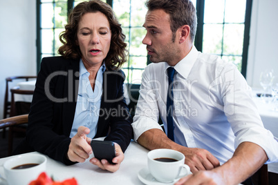 Business colleagues looking at mobile phone while having a meeti