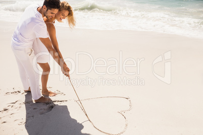 Couple drawing heart on sand