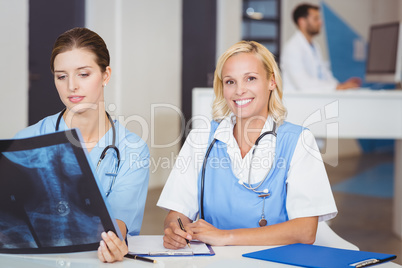 Portrait of smiling doctor with colleague examining X-ray