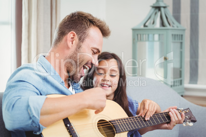 Father playing guitar with daughter